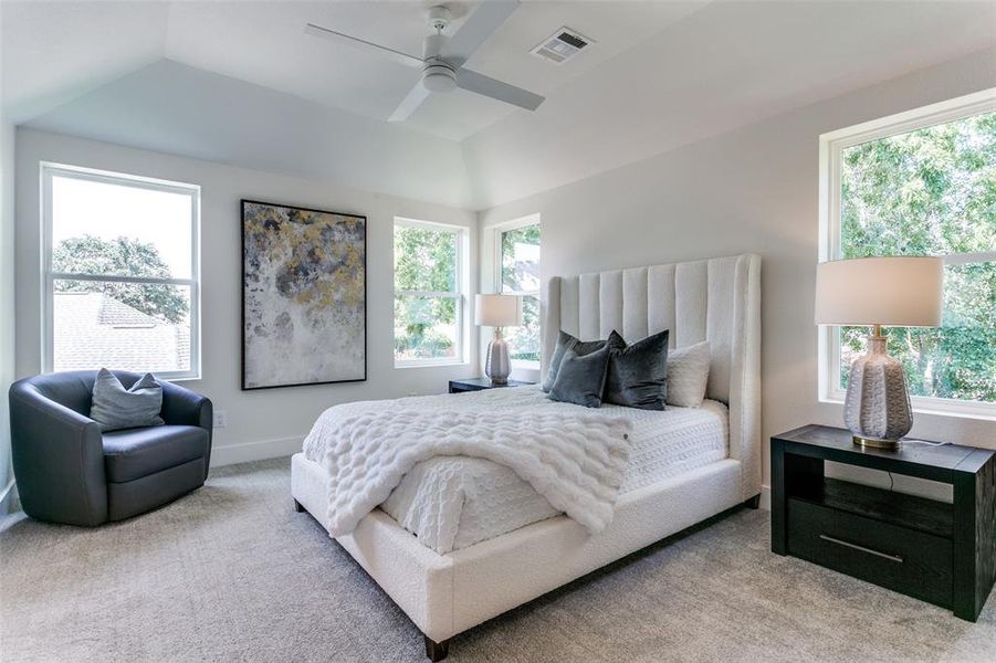 Carpeted bedroom featuring multiple windows, vaulted ceiling, and ceiling fan