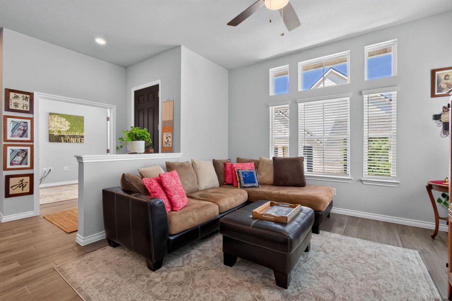 A comfortable living area with light-toned walls features rich wood flooring and abundant natural illumination. A comfortable living area with light-toned walls features rich wood flooring and abundant natural illumination.