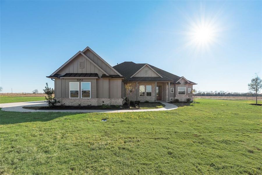 Craftsman-style house featuring a front yard, brick siding, and board and batten siding Craftsman-style house featuring a front yard, brick siding, and board and batten siding
