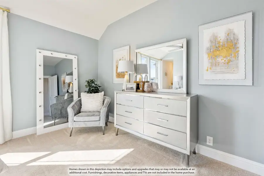 Bedroom with vaulted ceiling, white dresser, accent chair, and large lighted mirror on gray walls