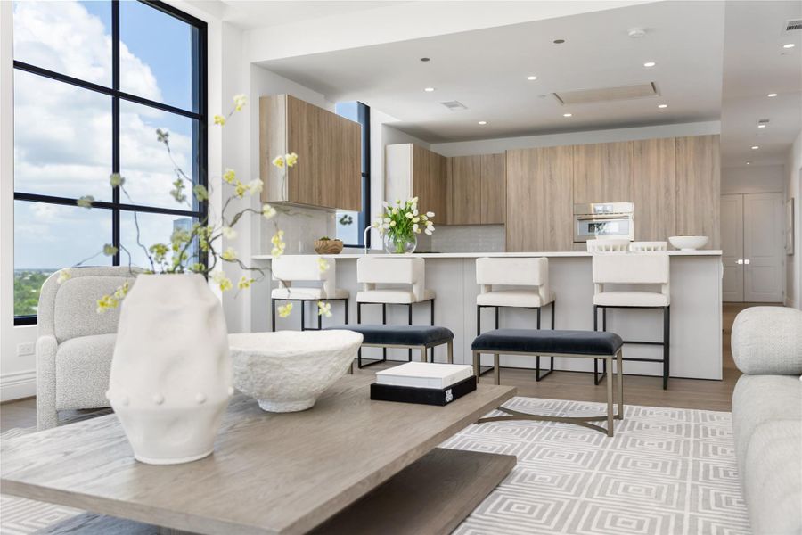 The kitchen is thoughtfully designed with sleek cabinetry, clean lines, and an expansive island with seating, seamlessly opening to the living area while enjoying natural light and city views.