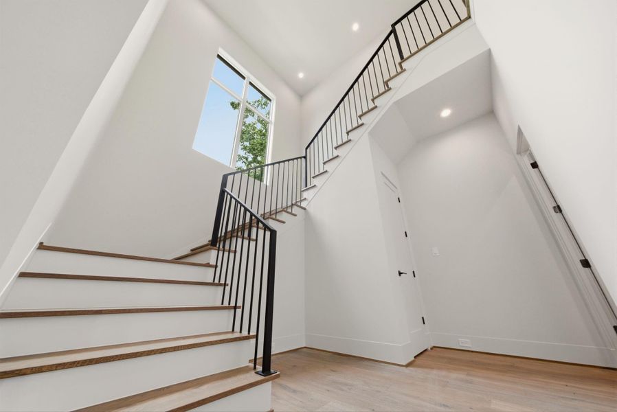 Dramatic stairwell with modern railing and natural light pouring through oversized window.