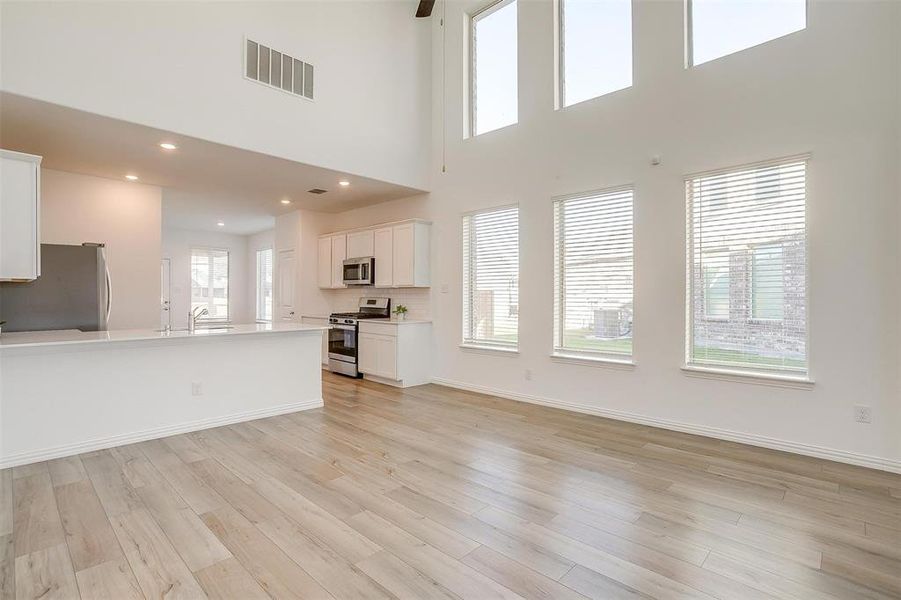 Unfurnished living room with light hardwood / wood-style flooring, a high ceiling, and sink