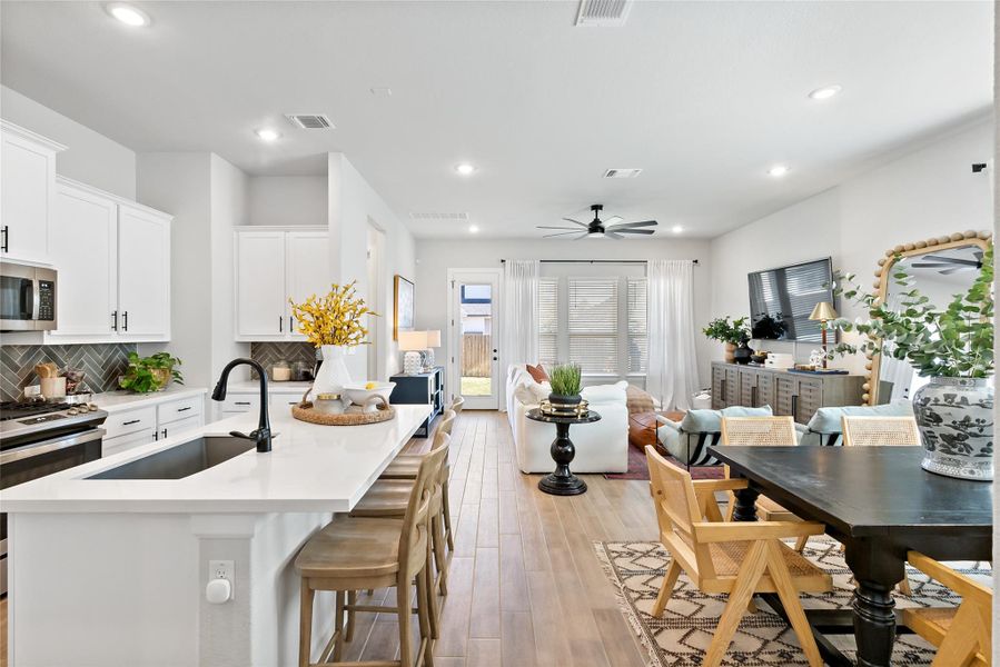 Kitchen featuring a breakfast bar area, white cabinets, stainless steel appliances, a center island with sink, and recessed lighting