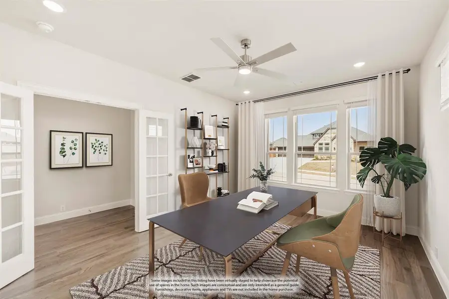 Home office with dark desk, leather chairs, ceiling fan, and large windows with natural light
