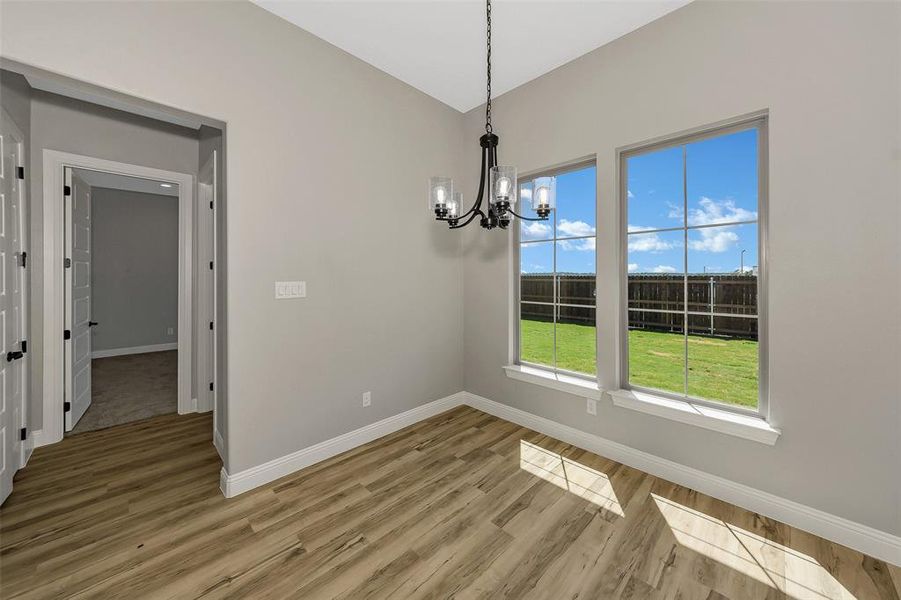 Unfurnished dining area with a chandelier, light wood-style floors, and vaulted ceiling