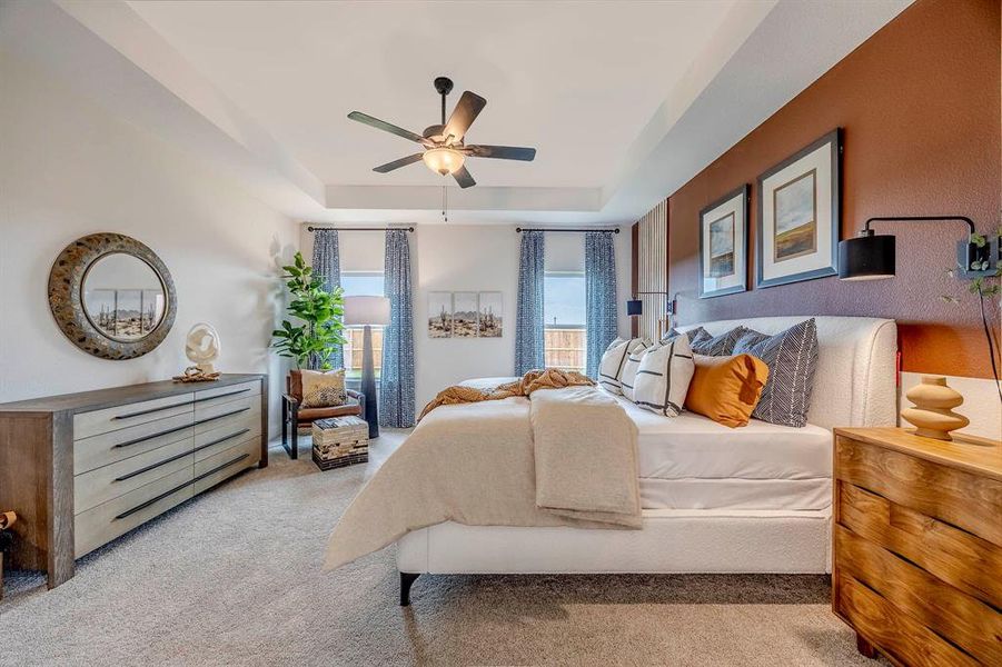 Bedroom with a tray ceiling, ceiling fan, and light colored carpet