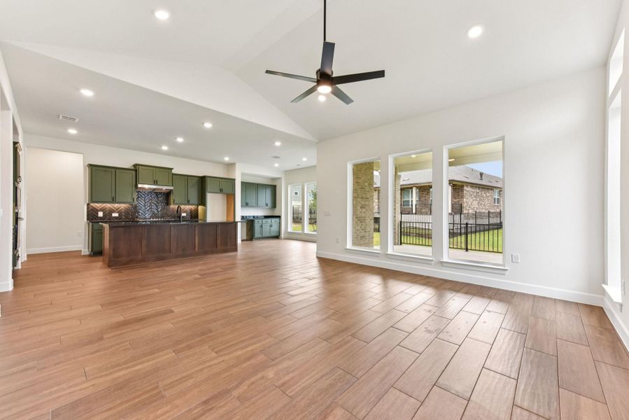 Unfurnished living room with wood finish floors, lofted ceiling, recessed lighting, and a ceiling fan