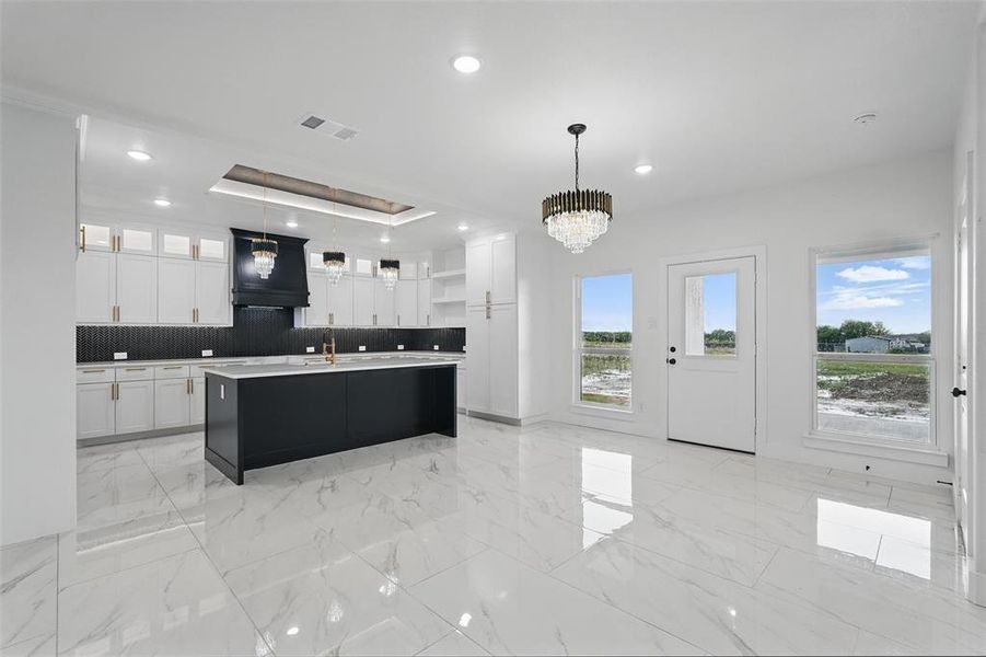 Kitchen with open shelves, premium range hood, light marble finish flooring, white cabinets, and recessed lighting Kitchen with open shelves, premium range hood, light marble finish flooring, white cabinets, and recessed lighting