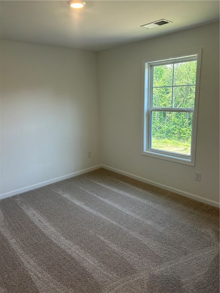 A well-lit bedroom features plush carpeting and a A well-lit bedroom features plush carpeting and a