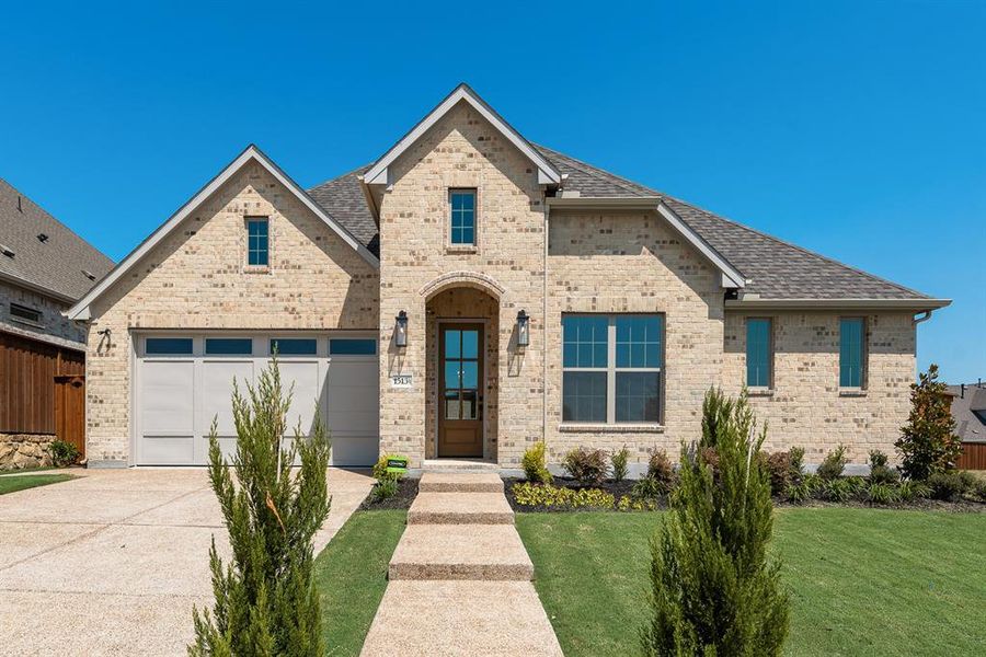 View of front of property featuring a shingled roof, concrete driveway, brick siding, and a garage