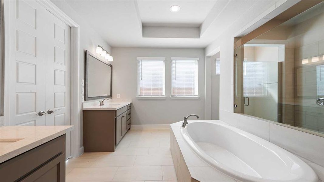 Bathroom with vanity, independent shower and bath, and a tray ceiling