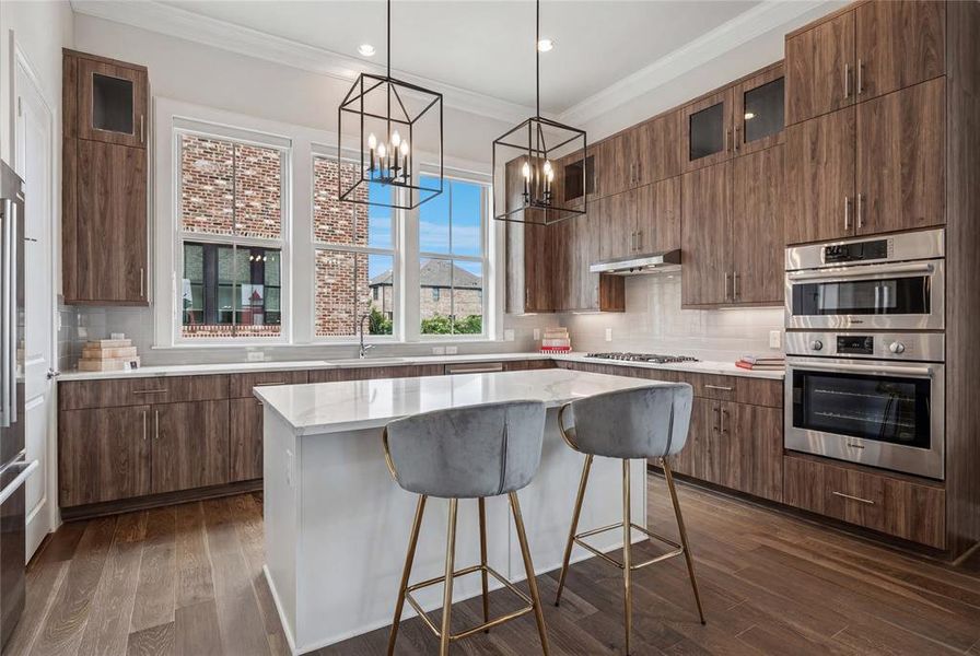 Gourmet kitchen featuring a central island with a white countertop, extensive wood-finish cabinetry, stainless steel double ovens, and a gas range