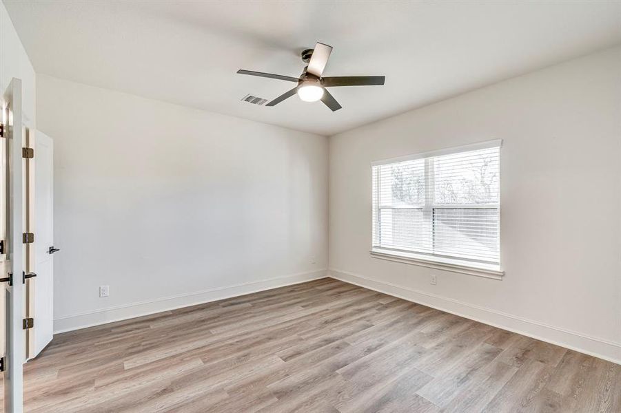 Spare room featuring baseboards, visible vents, ceiling fan, and light wood-type flooring Spare room featuring baseboards, visible vents, ceiling fan, and light wood-type flooring