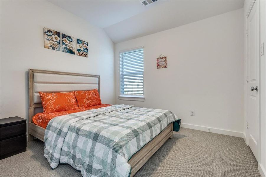Bedroom featuring light carpet and vaulted ceiling Bedroom featuring light carpet and vaulted ceiling