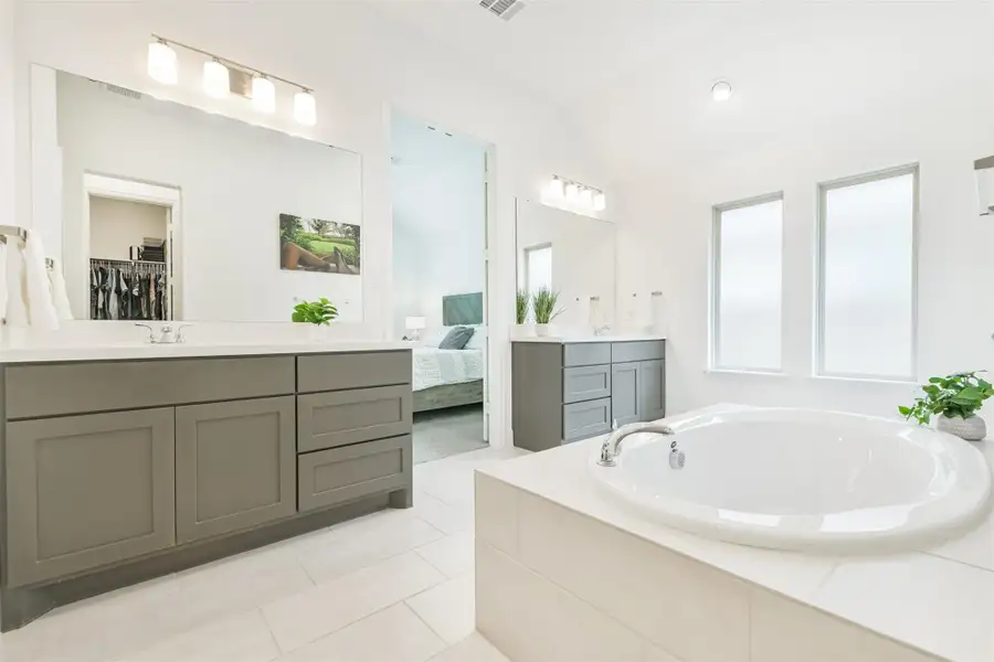 Well lit double vanities with ample storage space and large windows in this primary bath. Well lit double vanities with ample storage space and large windows in this primary bath.