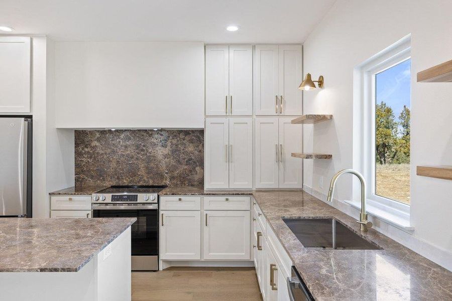 Kitchen with open shelves, stainless steel appliances, dark stone counters, white cabinets, and recessed lighting