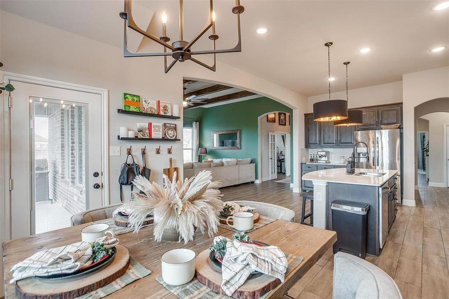 Dining room with beam ceiling, light hardwood / wood-style flooring, ceiling fan with notable chandelier, and sink