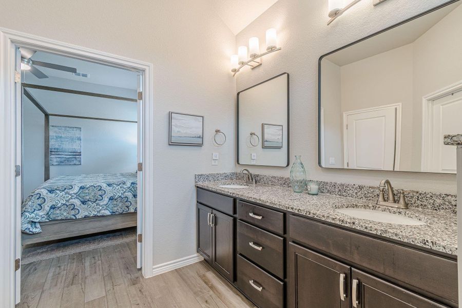 Ensuite bathroom with wood finished floors, baseboards, double vanity, and a ceiling fan