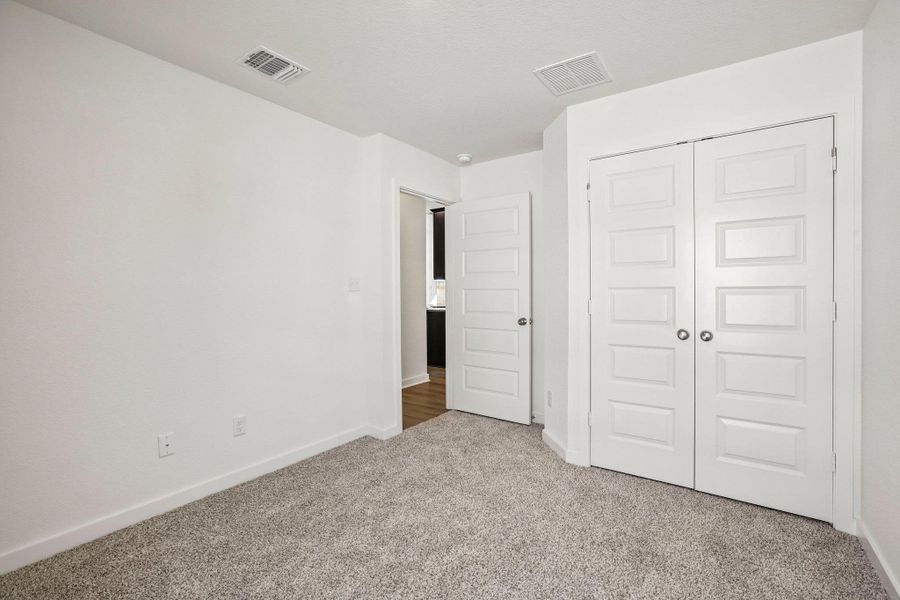 Plush carpeting and clean white walls anchor this versatile space featuring double closet doors.