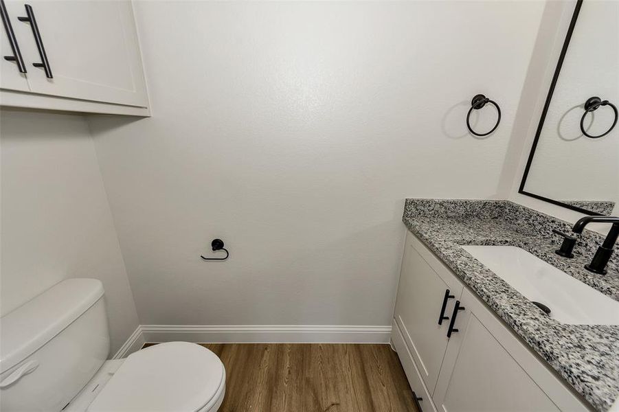 Half bathroom featuring vanity and wood finished floors