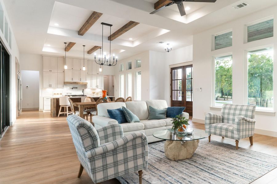 Living room with beamed ceiling, plenty of natural light, ceiling fan, a chandelier, and light wood finished floors Living room with beamed ceiling, plenty of natural light, ceiling fan, a chandelier, and light wood finished floors