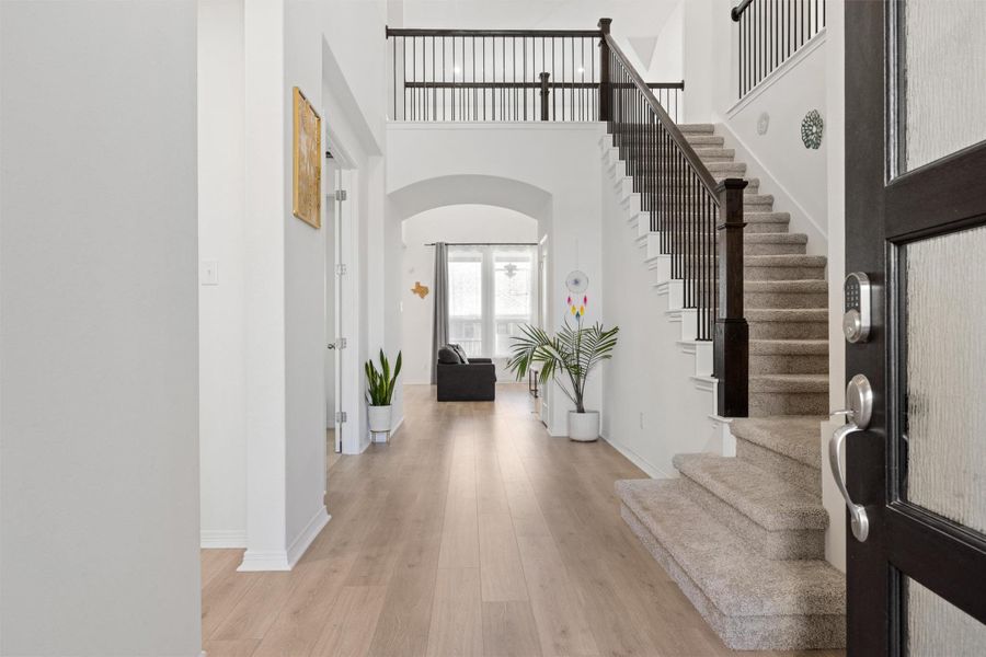 Entrance foyer featuring a high ceiling, light wood-style flooring, arched walkways, and stairway Entrance foyer featuring a high ceiling, light wood-style flooring, arched walkways, and stairway