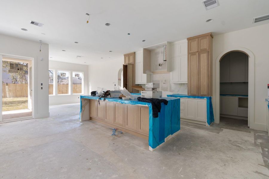 The dining area sits just off the kitchen and is wrapped in oversized windows overlooking the backyard, flooding the space with natural light and visually connecting the kitchen, dining, and living areas.