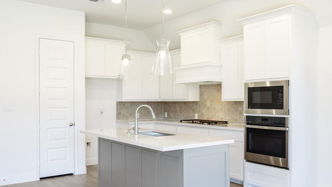 Kitchen with decorative backsplash, stainless steel appliances, pendant lighting, light stone countertops, and light wood-type flooring Kitchen with decorative backsplash, stainless steel appliances, pendant lighting, light stone countertops, and light wood-type flooring