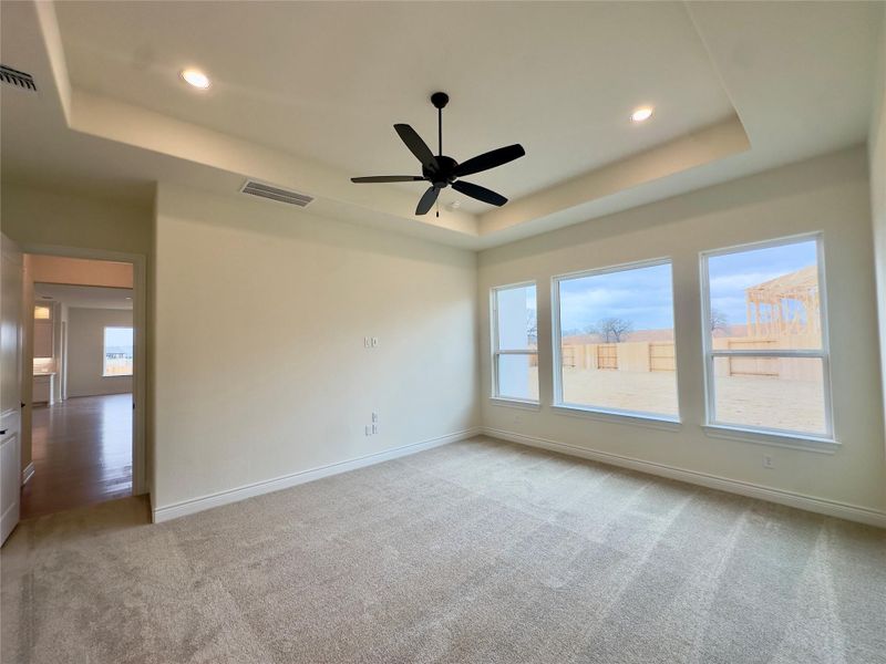 Unfurnished room featuring light colored carpet, a ceiling fan, recessed lighting, and a tray ceiling