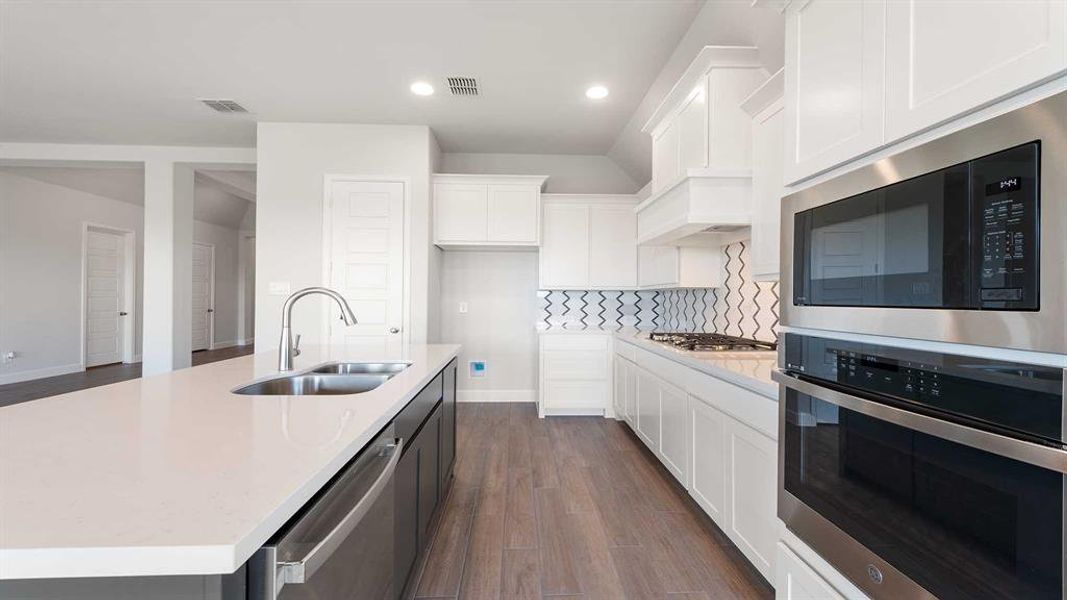 Kitchen with a kitchen island with sink, white cabinetry, sink, dark wood-type flooring, and appliances with stainless steel finishes