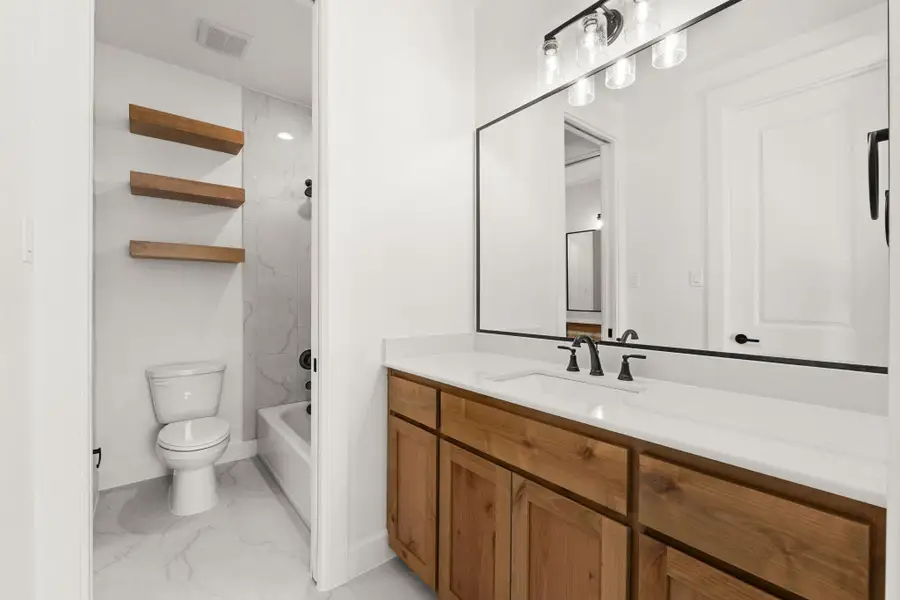 Full bath featuring shower / bathtub combination, vanity, and light marble finish floors