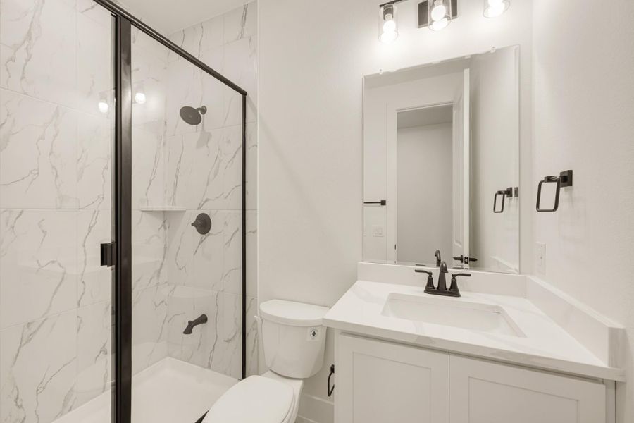 Bathroom with marble-tile walk-in shower, white vanity with quartz countertop, and matte black fixtures