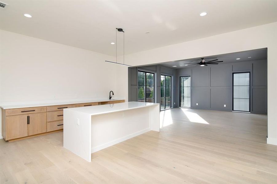 Kitchen with a kitchen island, light wood-type flooring, decorative light fixtures, sink, and ceiling fan