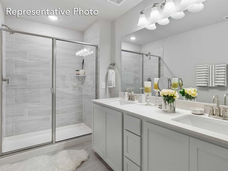 Bathroom featuring double vanity, a shower with shower door, and tile flooring