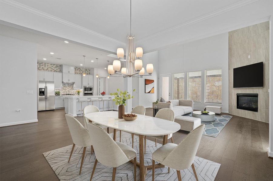 Dining area featuring crown molding, dark wood-style flooring, a tiled fireplace, and hanging lights Dining area featuring crown molding, dark wood-style flooring, a tiled fireplace, and hanging lights