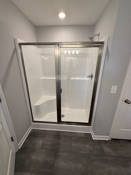 primary shower with a seat & shower door