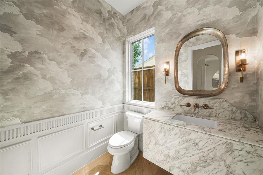 Powder room featuring a floating vanity with a stone countertop, an integrated rectangular sink, wall-mounted faucet, and an organically shaped mirror