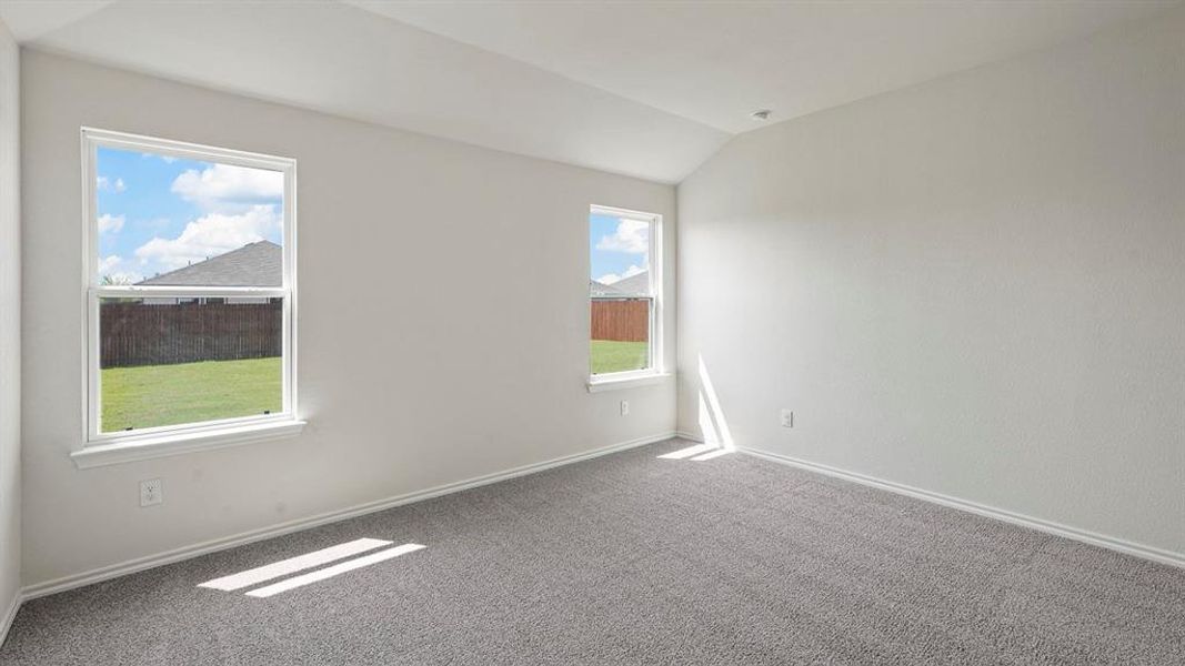 Carpeted room featuring two windows with white trim and a vaulted ceiling