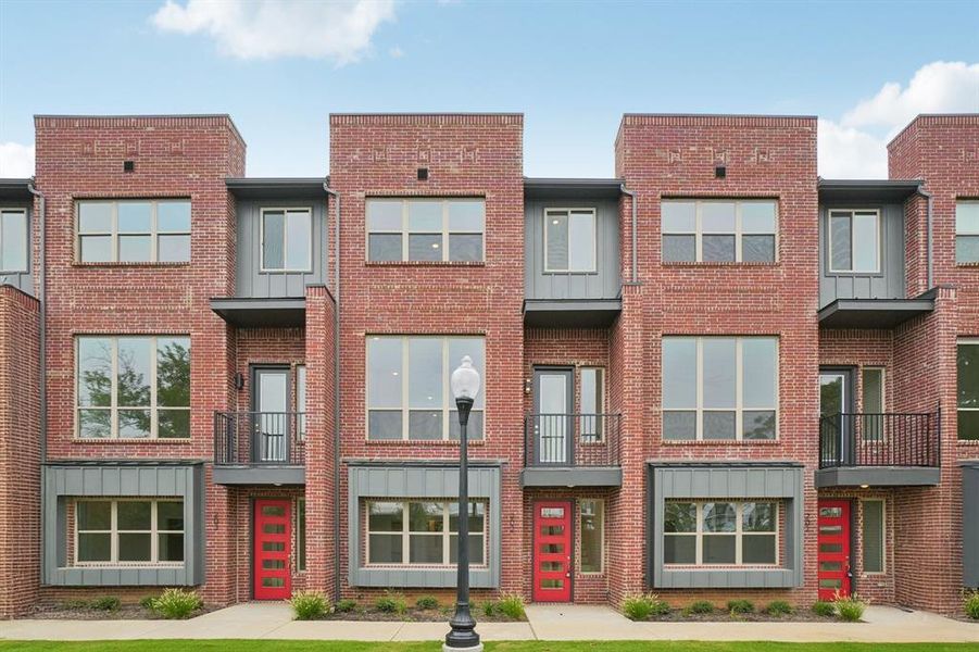 Contemporary house with board and batten siding, a balcony, and brick siding