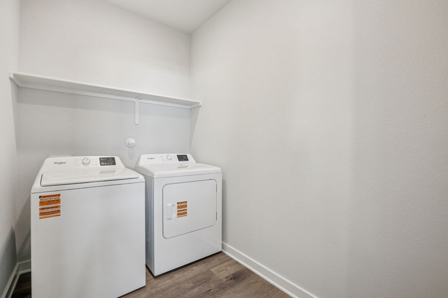 A white laundry room with a white wall and a white shelf.