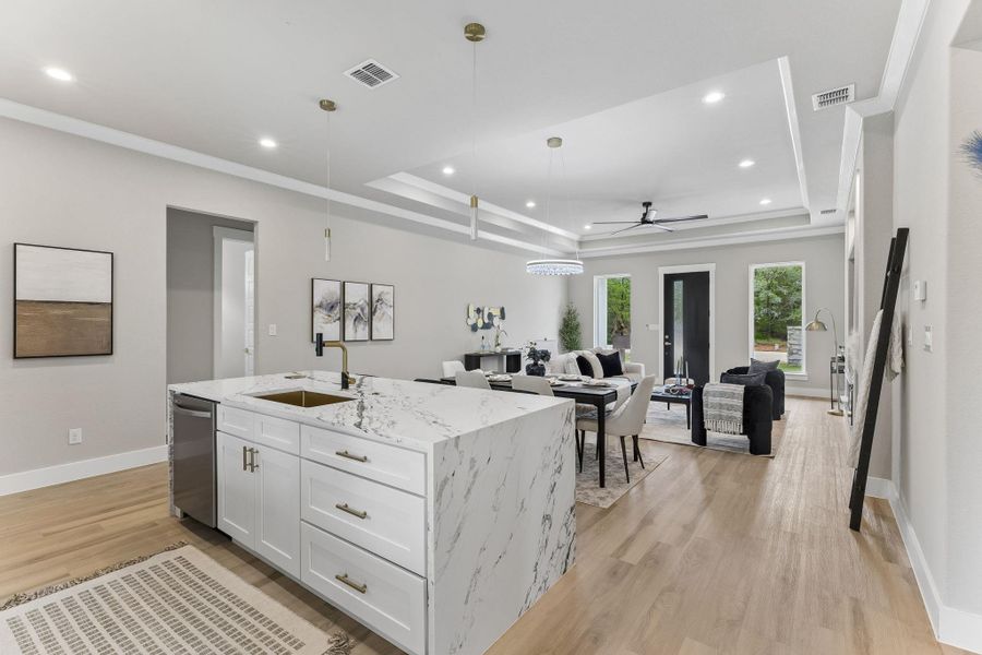 A gourmet kitchen island with luxurious marble counters opens to a spacious living and dining area.