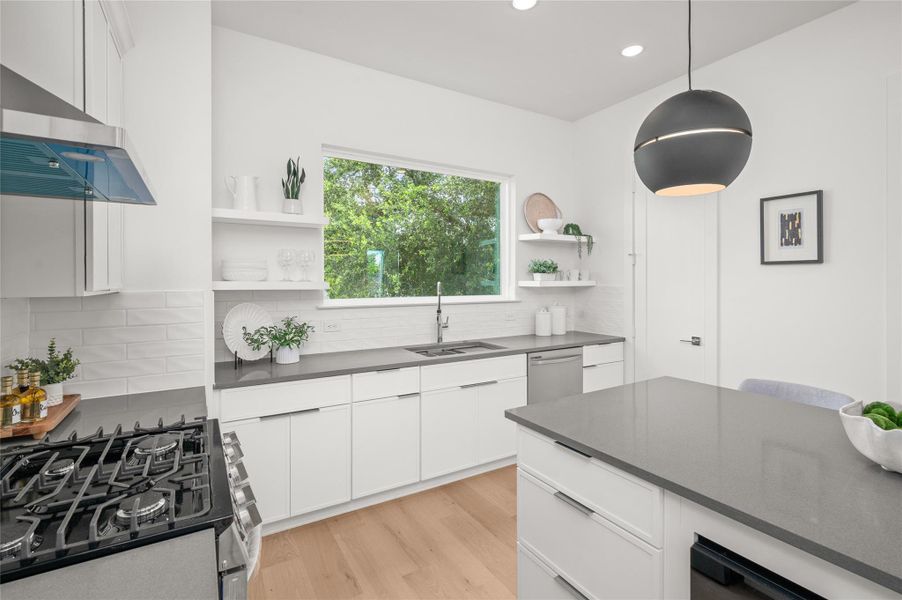 Open shelving and spacious pantry add both style and functionality to this light filled kitchen, while the large window brings natural greenery views.