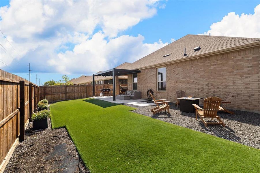 Fenced backyard with a patio area and an outdoor fire pit Fenced backyard with a patio area and an outdoor fire pit