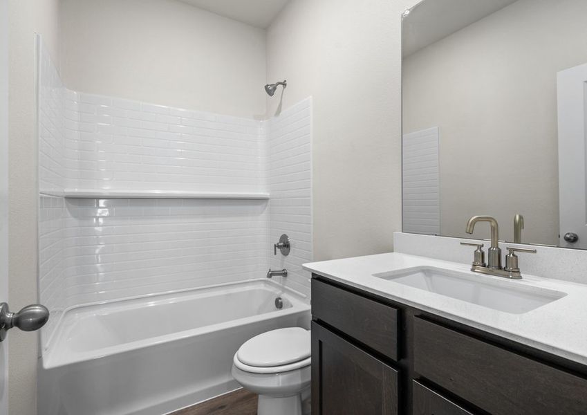 The secondary bathroom has a sprawling vanity and a shower-tub combo.