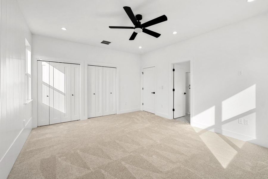 Unfurnished bedroom featuring multiple closets, recessed lighting, a ceiling fan, and light colored carpet