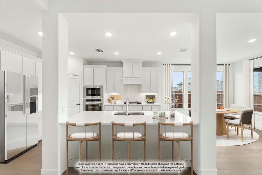 Open kitchen with white cabinets, large island with bar seating, stainless steel appliances, and dining area visible nearby. Open kitchen with white cabinets, large island with bar seating, stainless steel appliances, and dining area visible nearby.