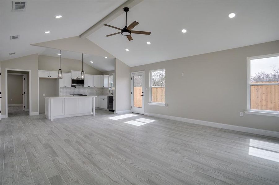 Unfurnished living room with visible vents, baseboards, beam ceiling, ceiling fan, and light wood-style floors