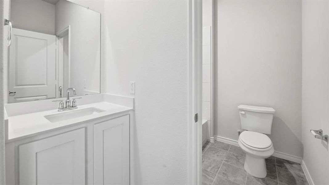 Bathroom featuring a white vanity with integrated sink, chrome faucet, and expansive mirror