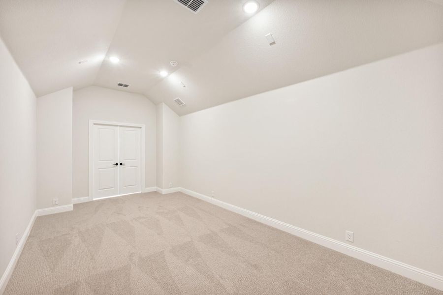 Empty bedroom with vaulted ceiling, recessed lighting, carpet flooring, and double doors